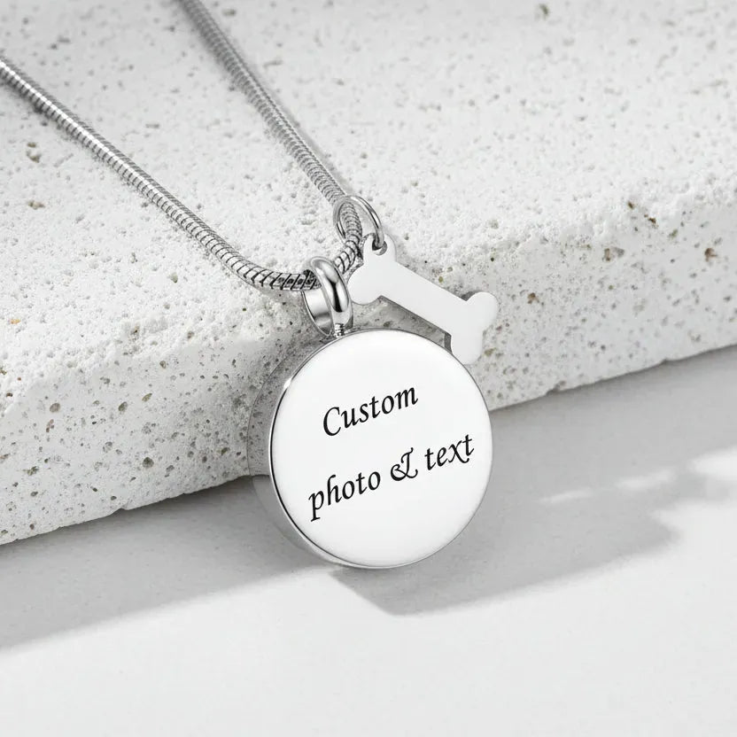 Silver necklace with a round pendant and bone-shaped tag on a white background