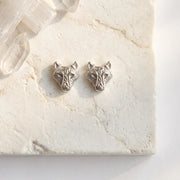Silver wolf head stud earrings on marble — spirit animal jewelry for courage and instinct