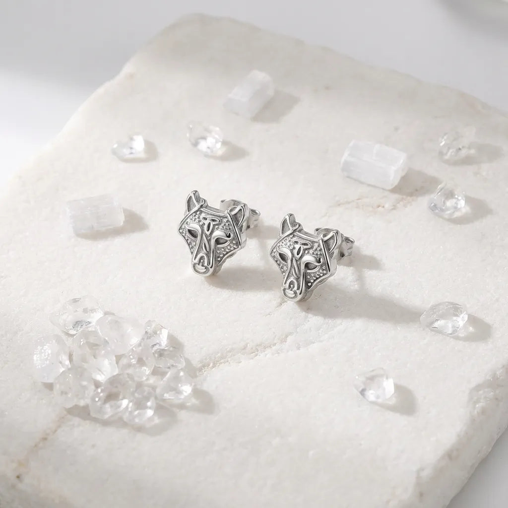 Silver horse head earrings on a white stone surface with clear crystals.