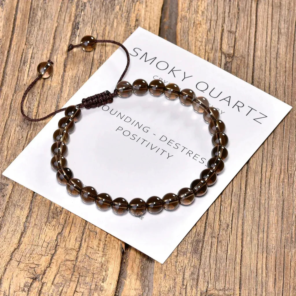 Smoky quartz bracelet on a wooden surface with a card detailing its properties.