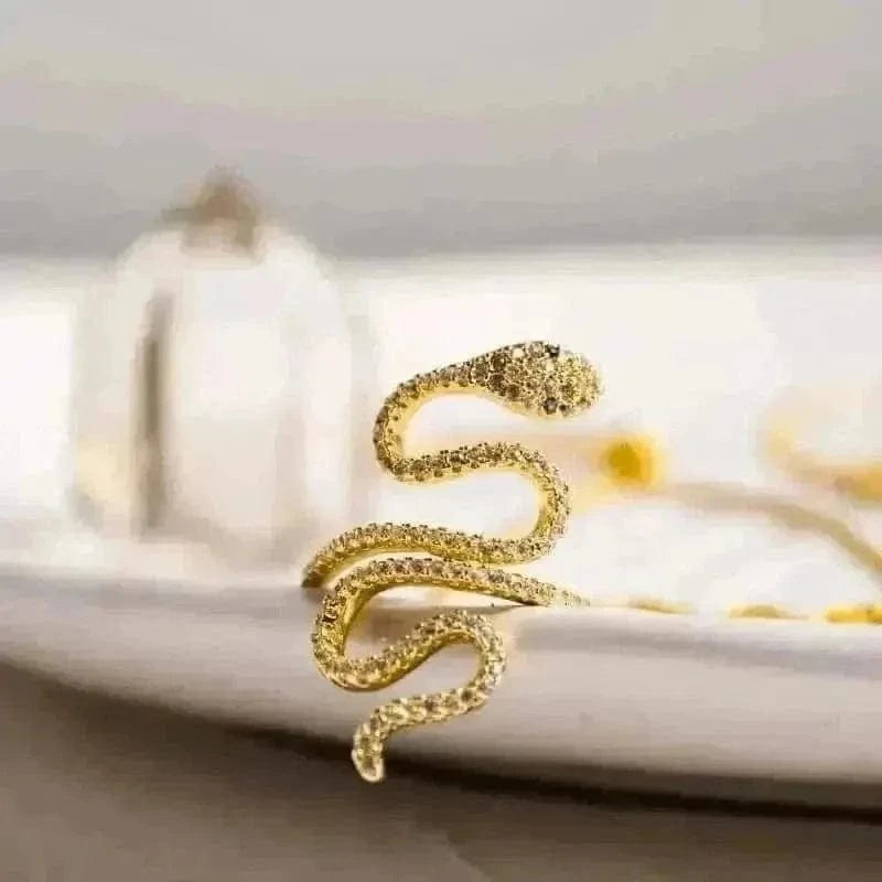 Gold snake-shaped earring on a white surface