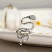 Silver snake-shaped earring on a blurred background