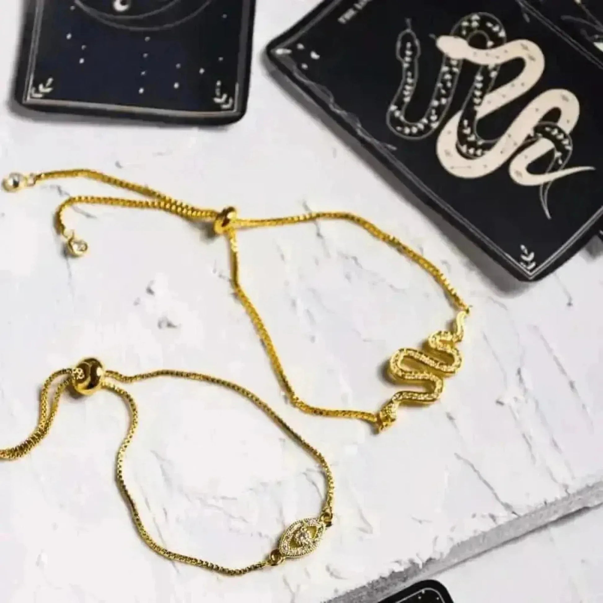 Gold bracelet on a marble surface with tarot cards in the background