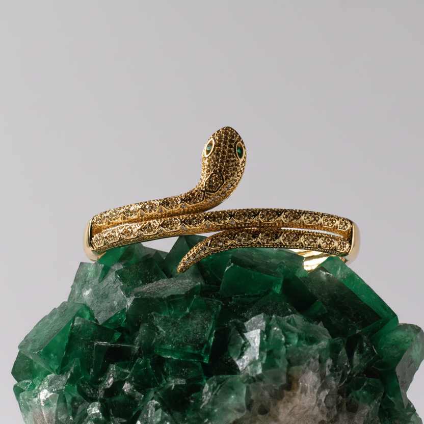 Gold snake-shaped brooch on a green crystal background