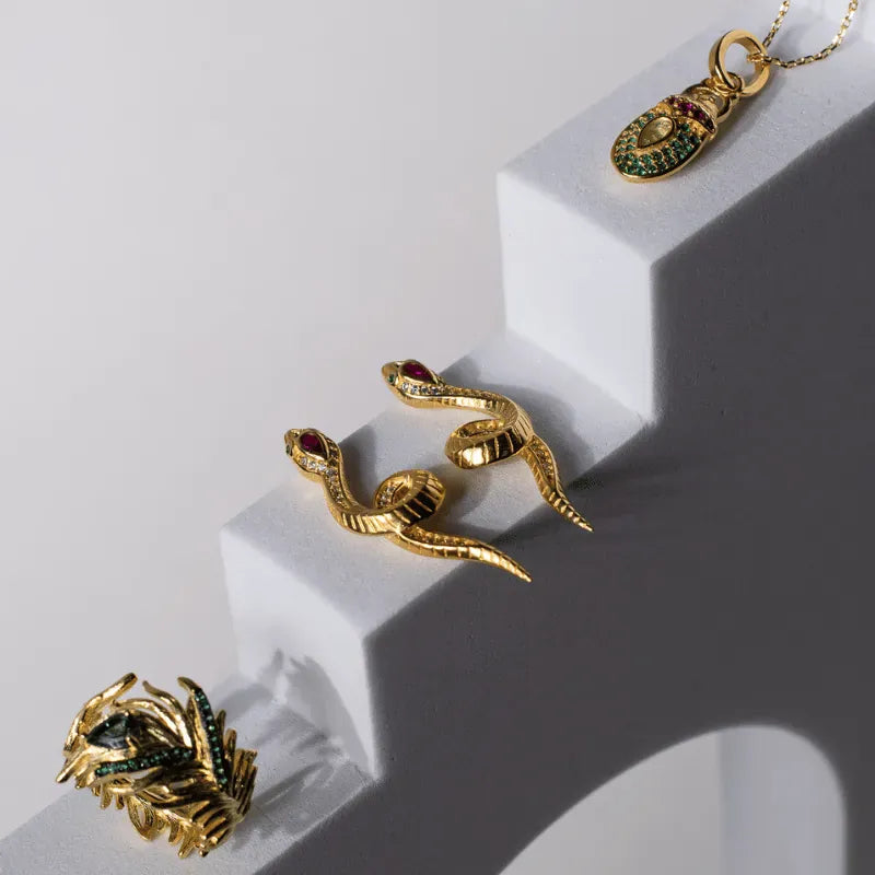 Gold jewelry set including earrings and a ring on a white surface