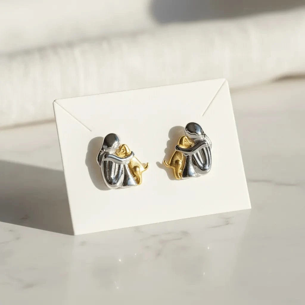 Pair of silver and gold earrings on a white card with a marble background