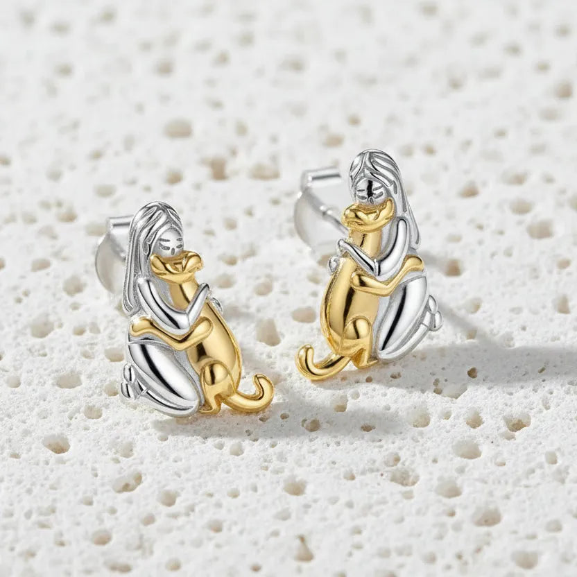Pair of dog-shaped earrings in gold and silver on a white background