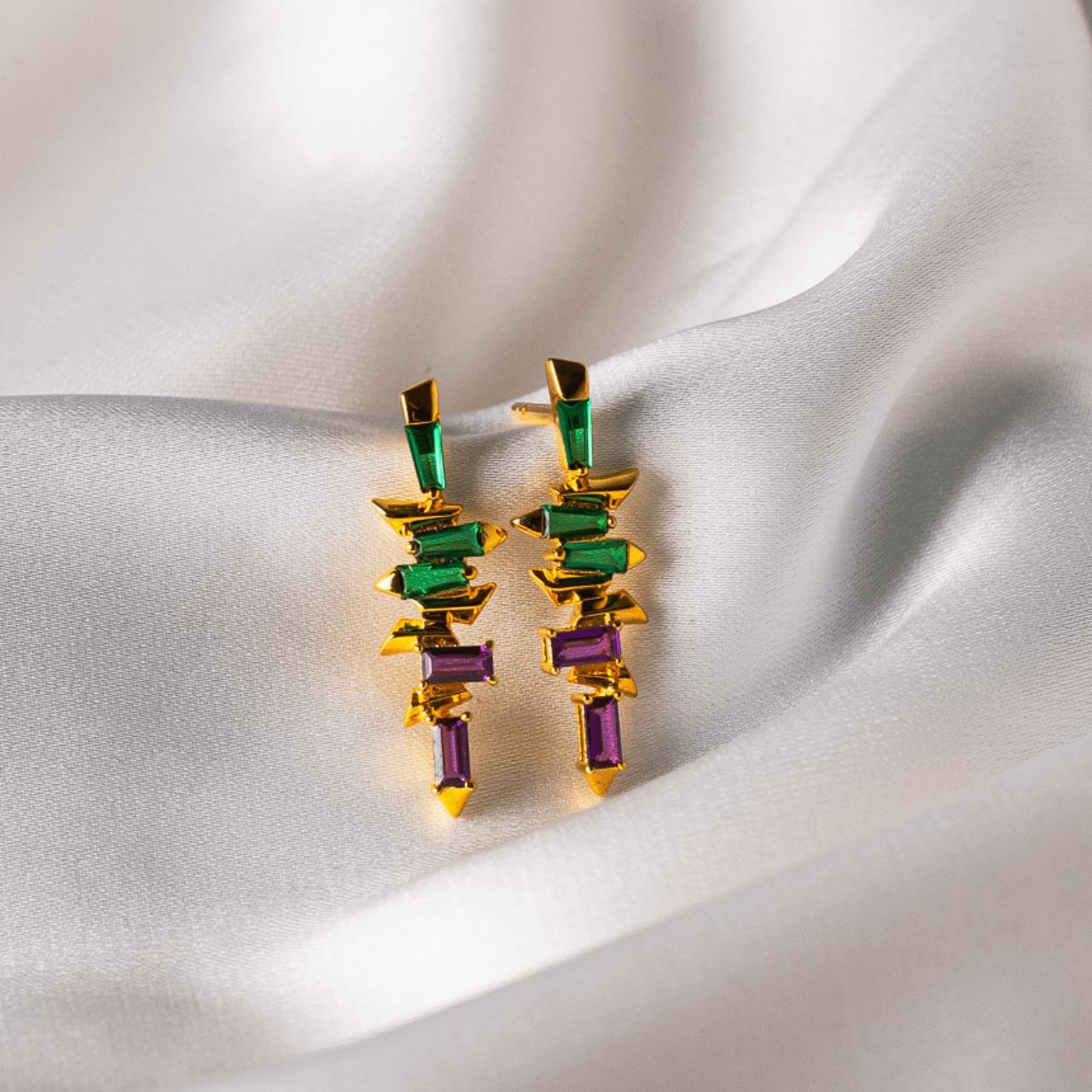 Colorful geometric earrings on a soft fabric background