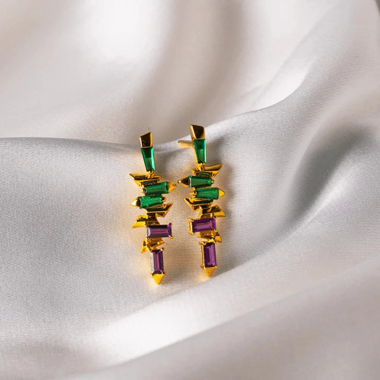 Colorful geometric earrings on a soft fabric background