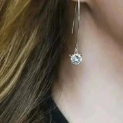 Close-up of a silver earring with a clear gemstone worn by a person.