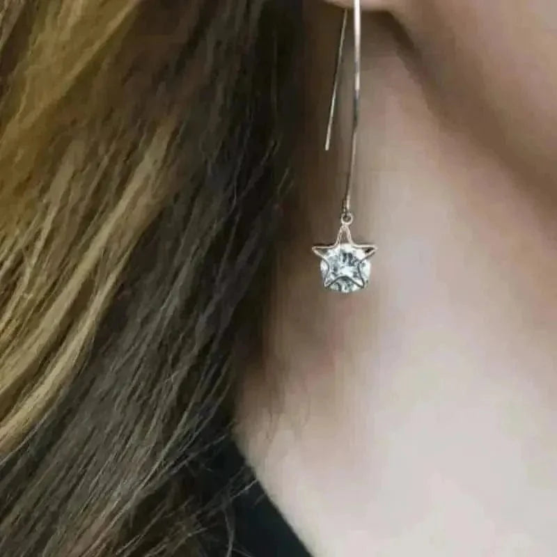 Close-up of a silver earring with a clear gemstone worn by a person.