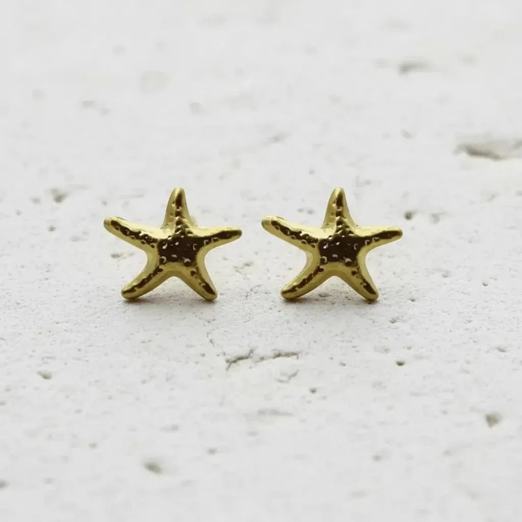 Gold starfish earrings on a textured white background
