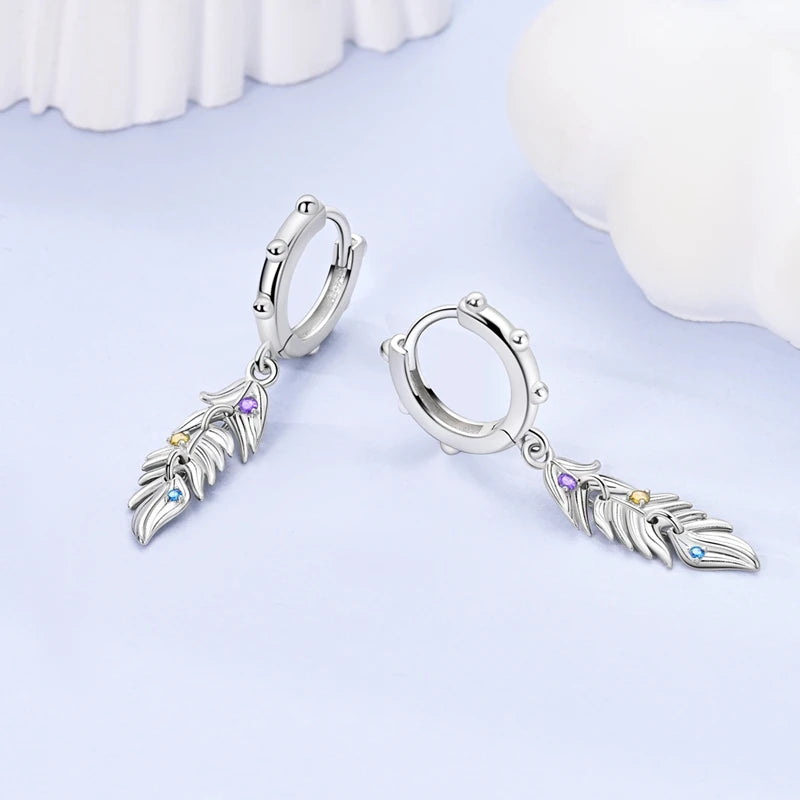 Sterling silver feather drop earrings on a plain background