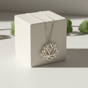Sterling silver lotus flower pendant necklace on a display block — spiritual symbol jewelry for renewal