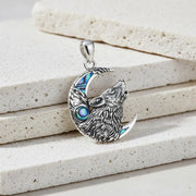 Silver pendant with wolf design on a textured stone surface