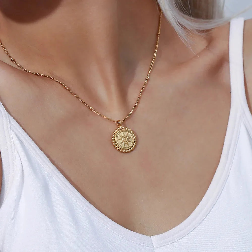 Hammered gold sun medallion pendant necklace on curb chain, styled on woman