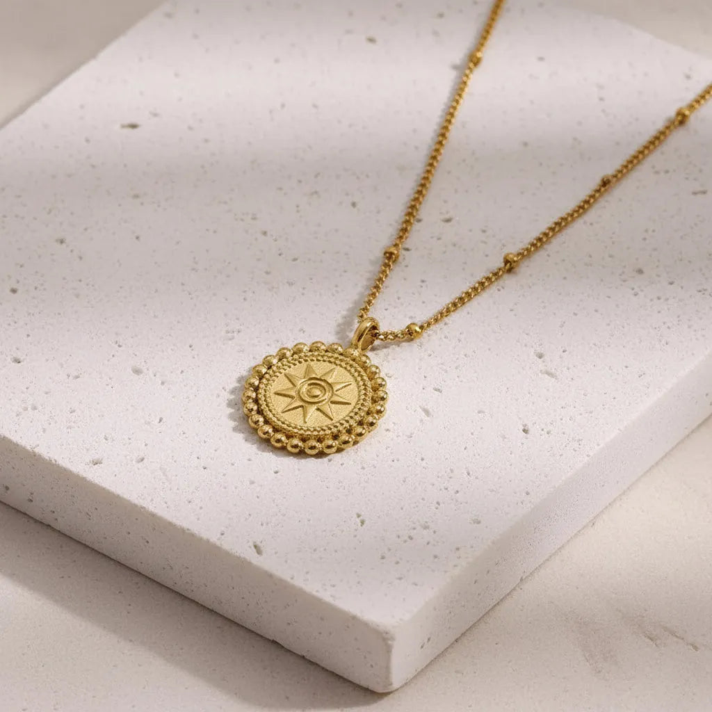 Gold necklace with a circular pendant on a white fabric background
