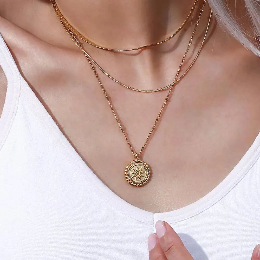 Hammered gold sun medallion pendant necklace on curb chain, styled on sandstone — 18K gold PVD stainless steel celestial jewelry