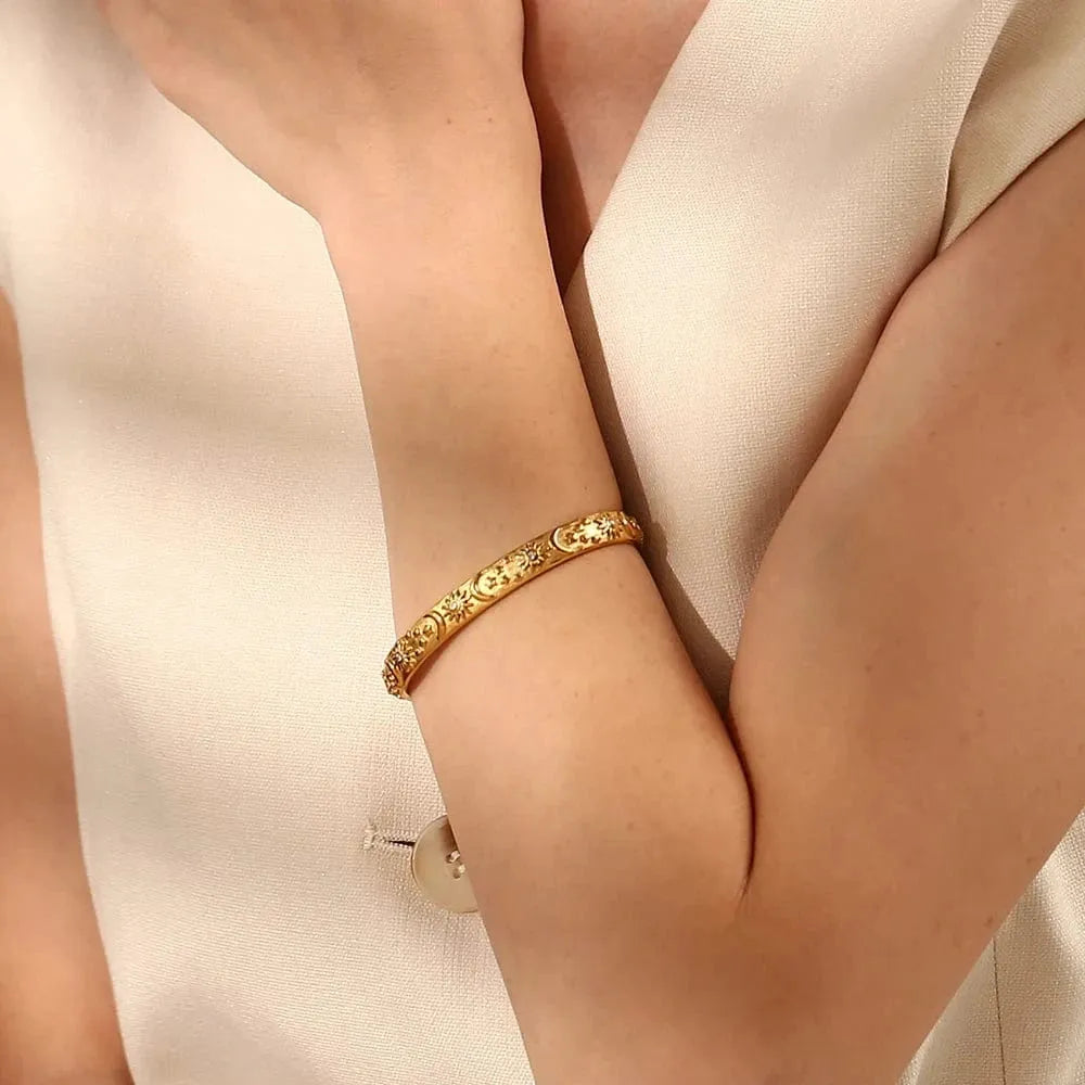 Gold bracelet on a person's wrist with a neutral background