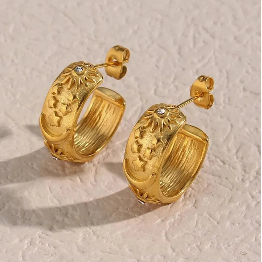 Pair of gold hoop earrings on a textured beige background