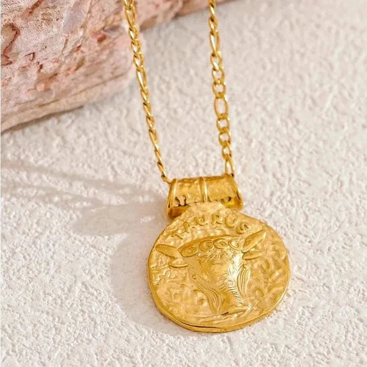 Gold necklace with a bull pendant on a textured surface