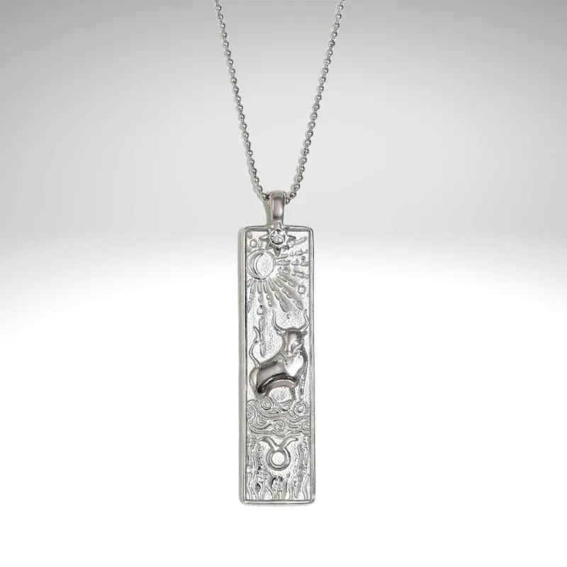 Silver pendant with intricate design on a chain against a light gray background