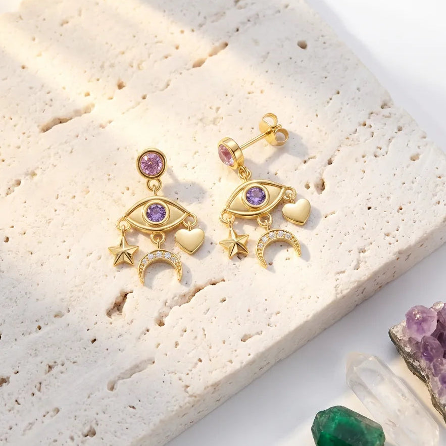 Gold earrings with gemstones on a textured surface