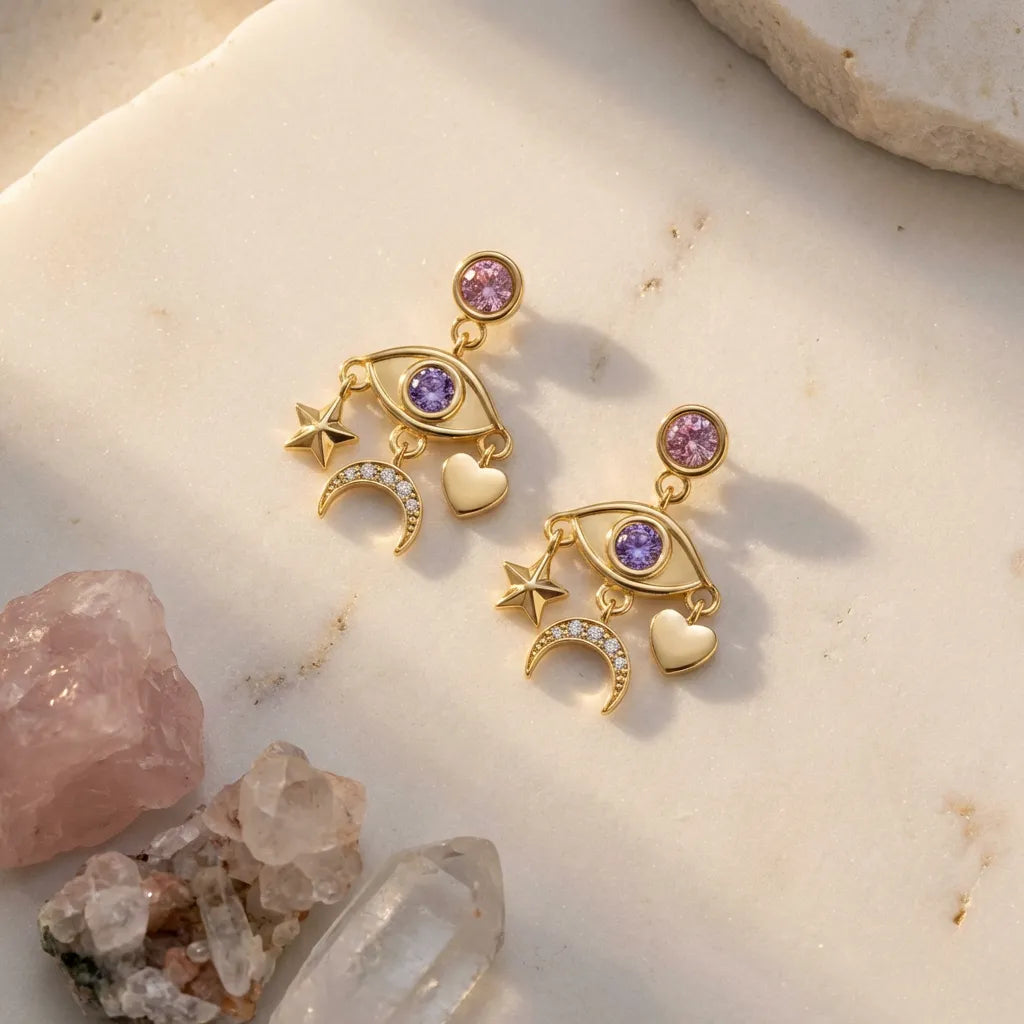 Gold earrings with purple gemstones on a stone surface