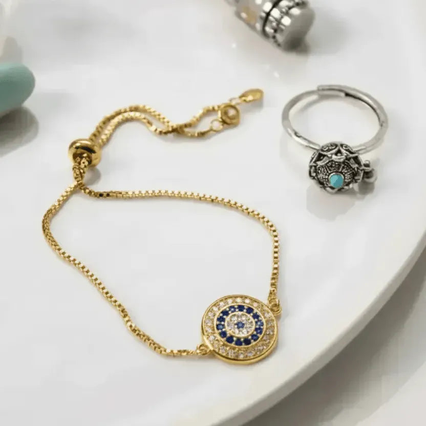 Gold bracelet with a circular design featuring blue stones on a white surface.