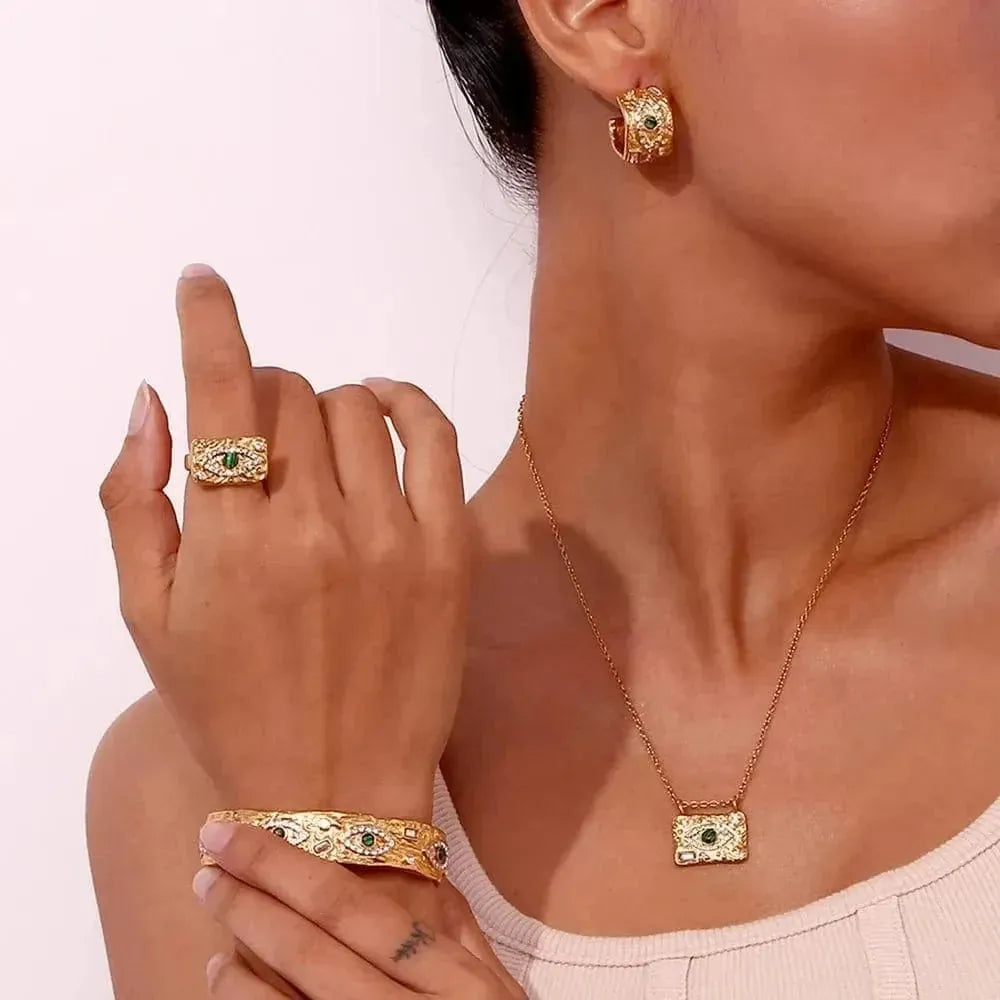 Gold jewelry set including ring, bracelet, and necklace on a model against a light background