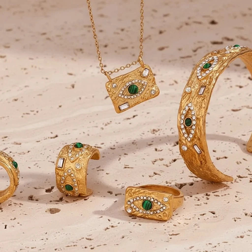 Gold jewelry set with rings, a necklace, and bracelet on a textured surface.