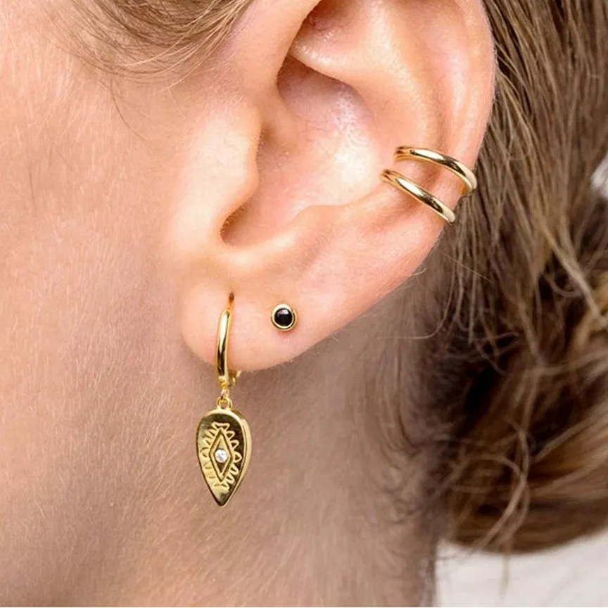 Close-up of an ear wearing gold hoop earrings with a blurred background