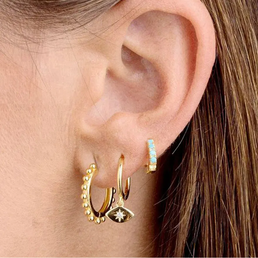 Close-up of an ear wearing gold hoop earrings with a visible brand logo.