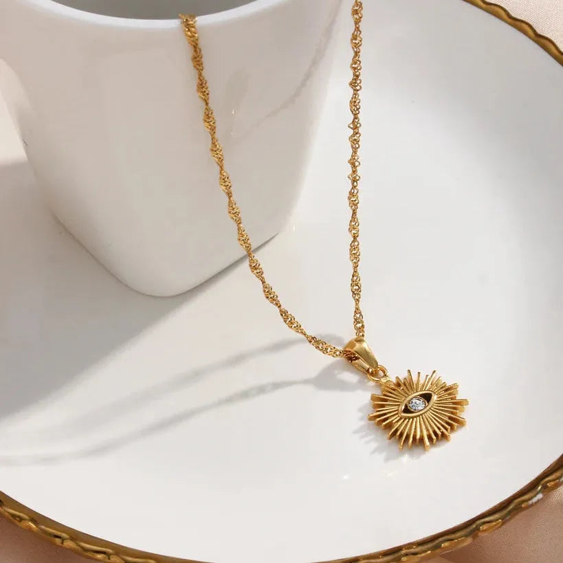 Gold necklace with a sunflower pendant on a white dish
