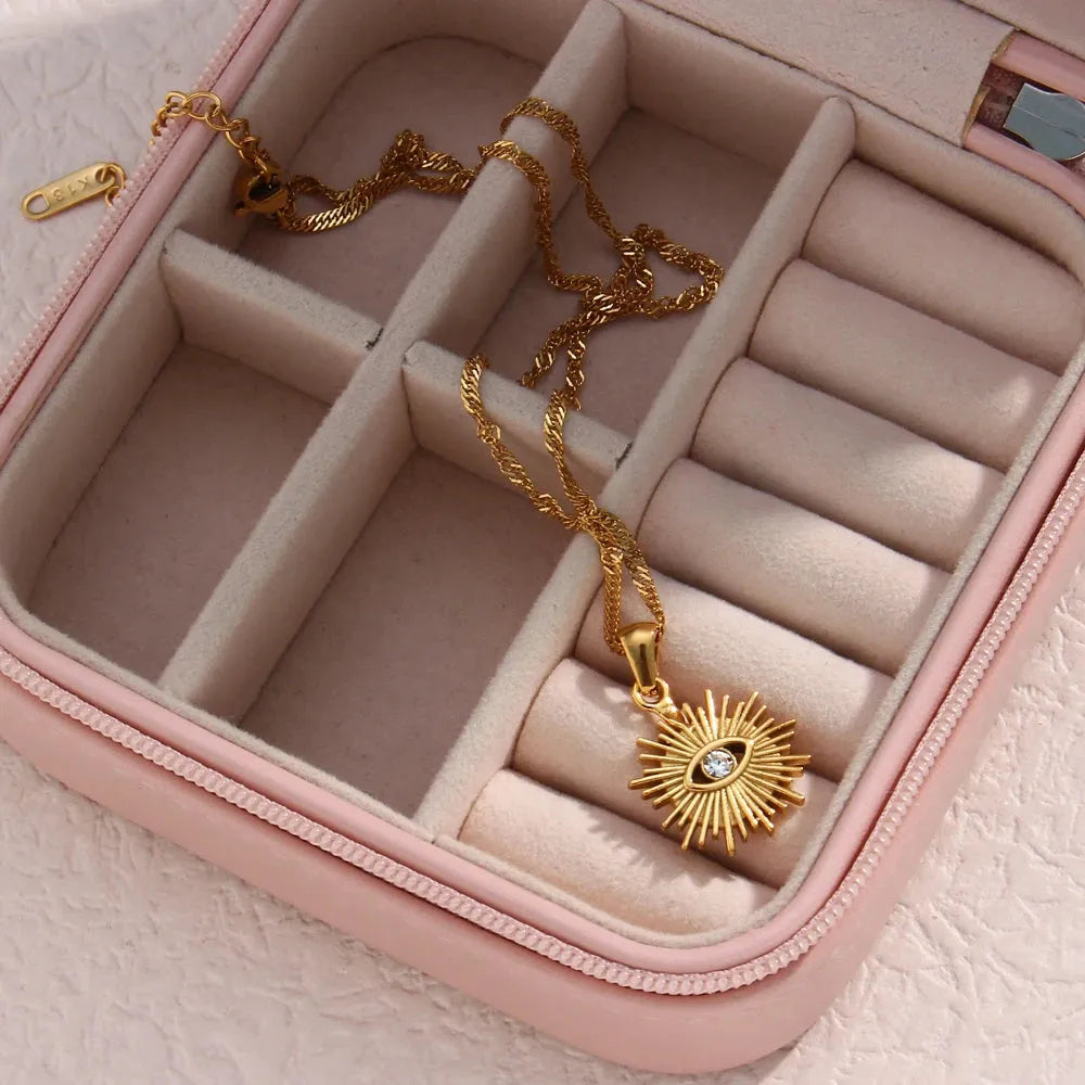 Gold necklace with a sun design pendant in a pink jewelry box.