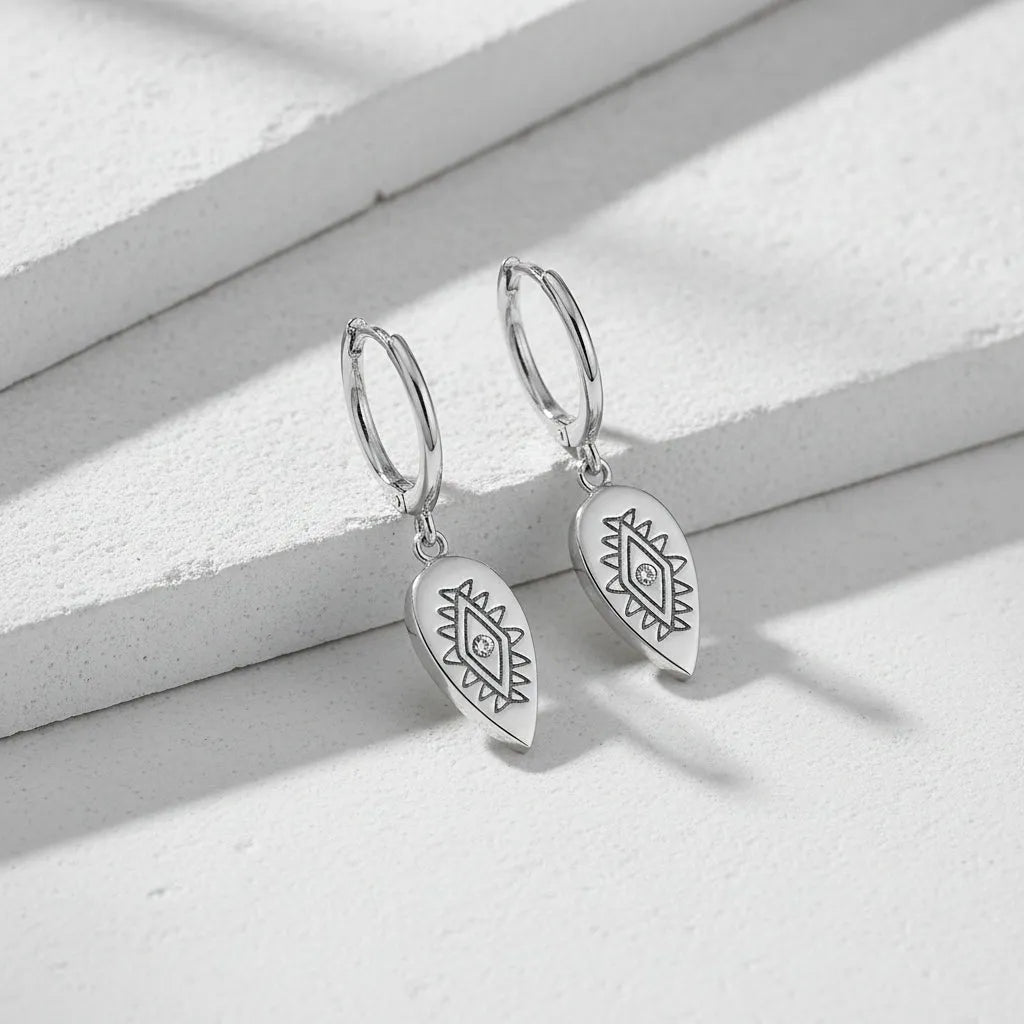 Silver earrings with geometric designs on a white background 