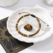 Tiger's eye beaded bracelet on a white dish with a card labeled 'Strength'.