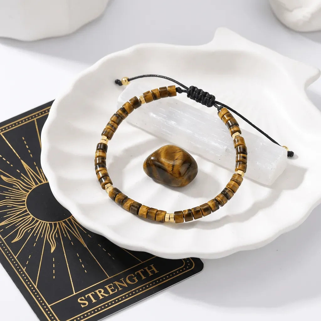 Tiger's eye beaded bracelet on a white dish with a card labeled 'Strength'.