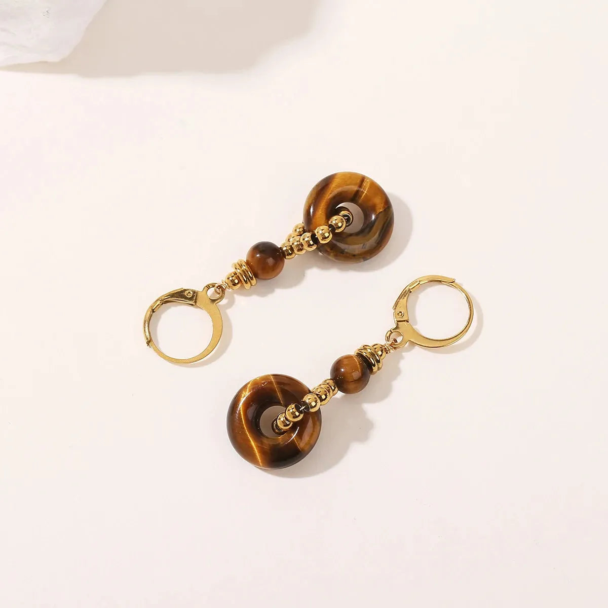 Pair of tiger eye stone earrings with gold accents on a light background