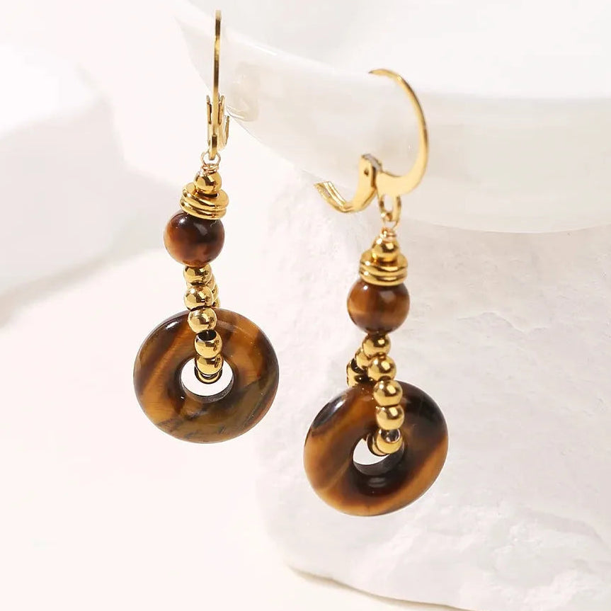 Gold and brown earrings on a white dish tiger eye earrings