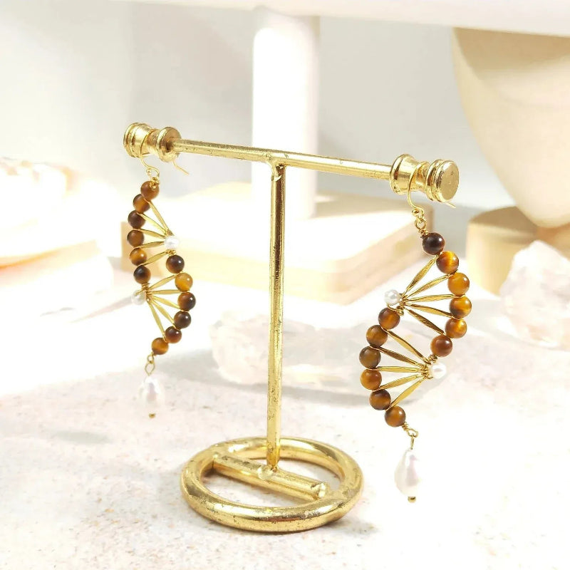 Gold and brown beaded earrings on a gold stand with a soft background