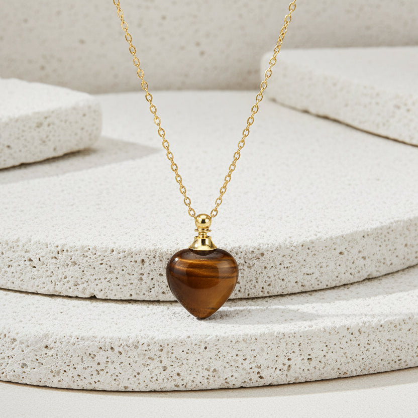 Gold necklace with a heart-shaped brown pendant on a white background
