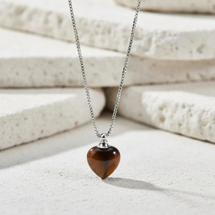 Heart-shaped amber pendant on a silver chain against a white background