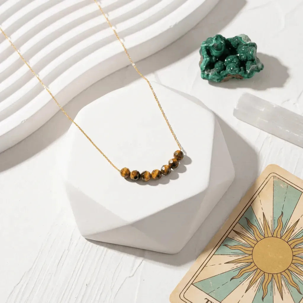 Necklace with brown beads on a white surface with a tarot card and crystal.