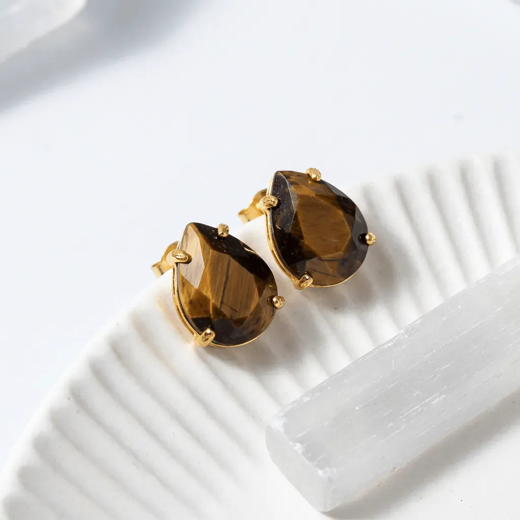 Pair of gold earrings with brown gemstones on a white surface