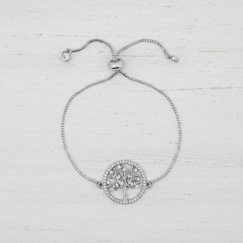 Silver bracelet with a tree of life design on a light wooden background