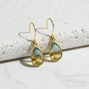 green yellow gold earrings on white stone background