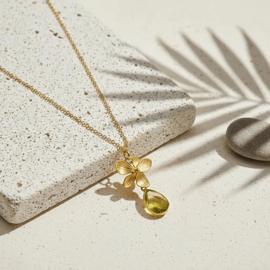 Gold necklace with a floral pendant on a textured stone surface