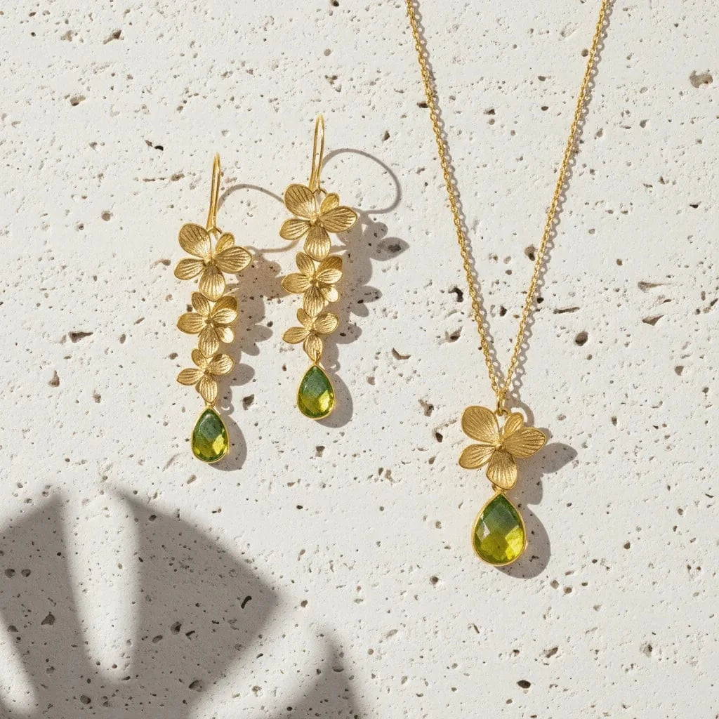 Gold jewelry set with floral designs and green stones on a textured surface