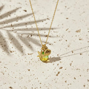 Gold necklace with a green pendant on a beige surface